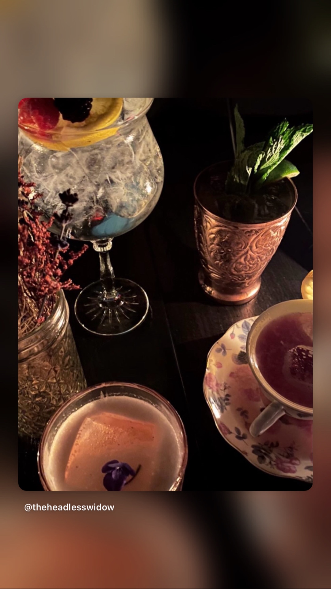 A table of cocktails at Headless Widow: a berry goblet, a copper julep cup and a teacup pour