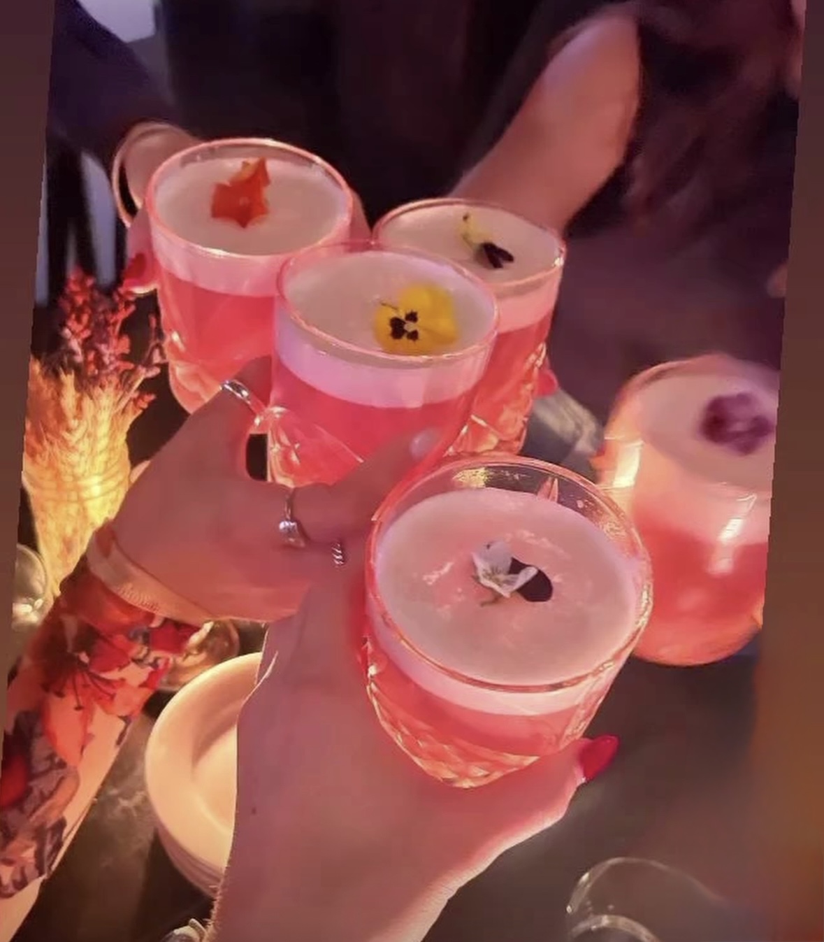 Guests toasting flower-topped cocktails at Headless Widow