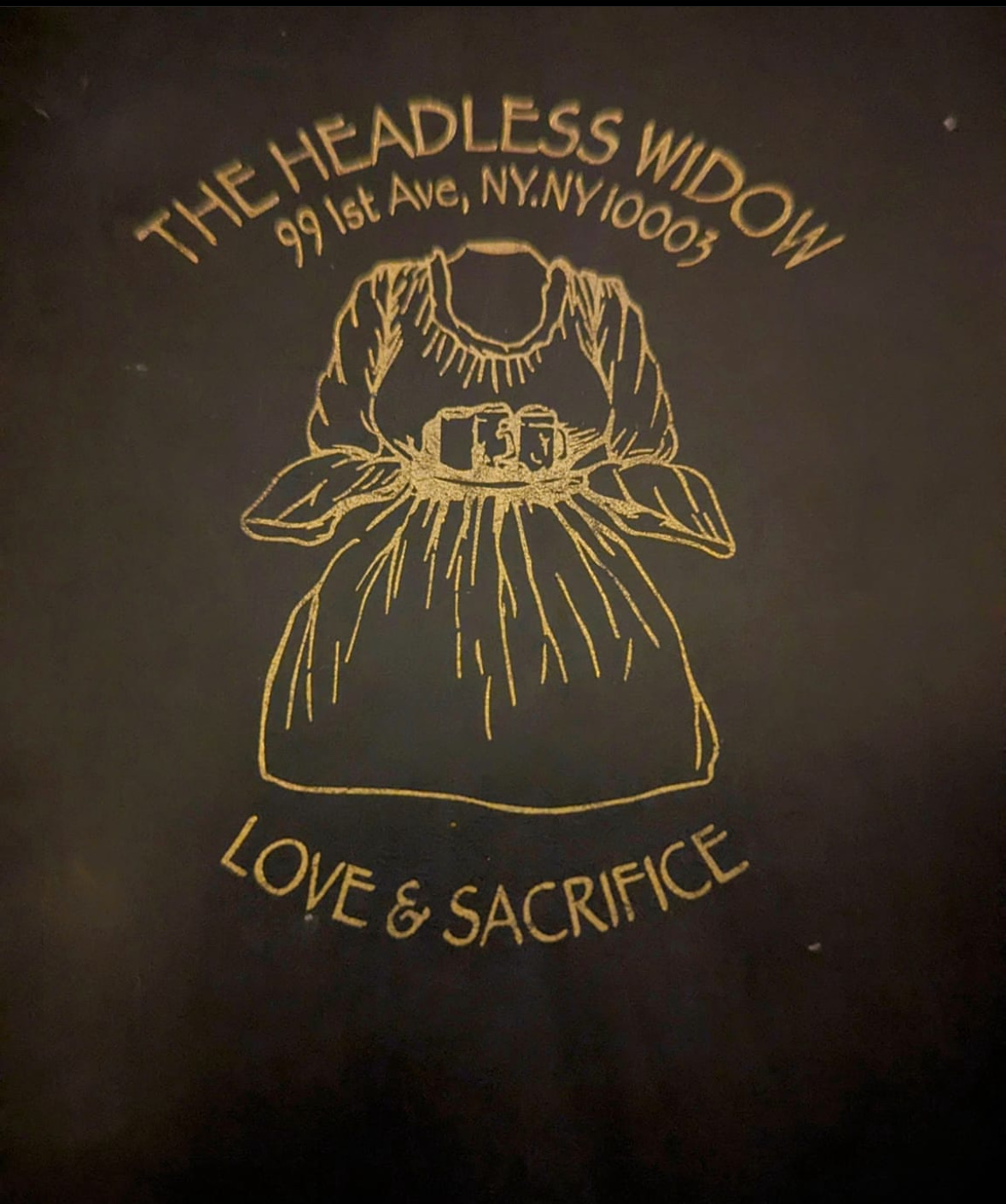 The Headless Widow crest: a gold headless dress above the words Love & Sacrifice, 99 1st Ave, NY NY 10003